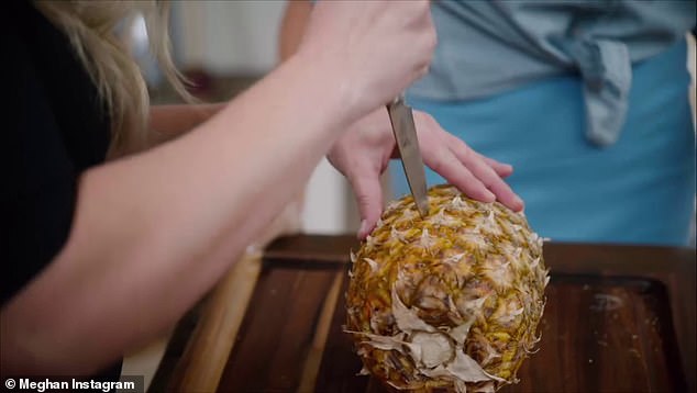 Meghan cuts around the pattern on the outside of the pineapple, and uses the skin to pull out a chunk of the fruit