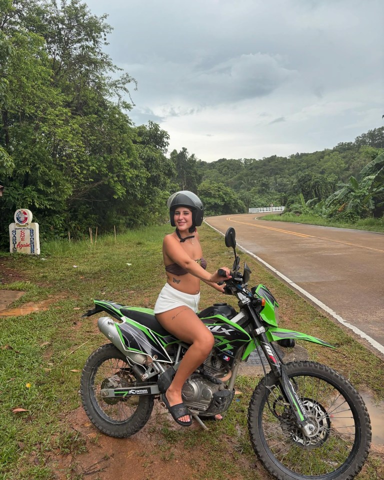 Young woman sitting on a green motorcycle in Thailand.
