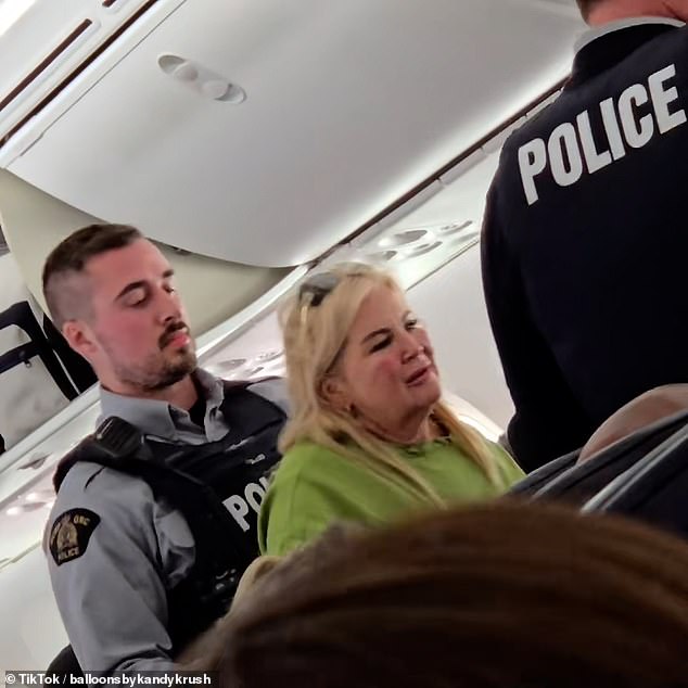 Two officers are seen guiding the older woman down the aisle as she screamed and yelled