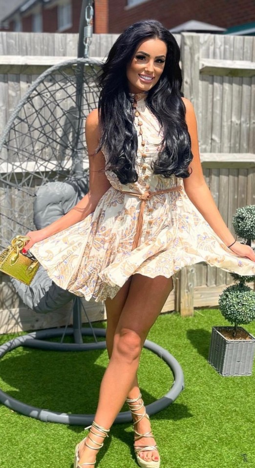 a woman in a white dress is standing in front of a wicker chair