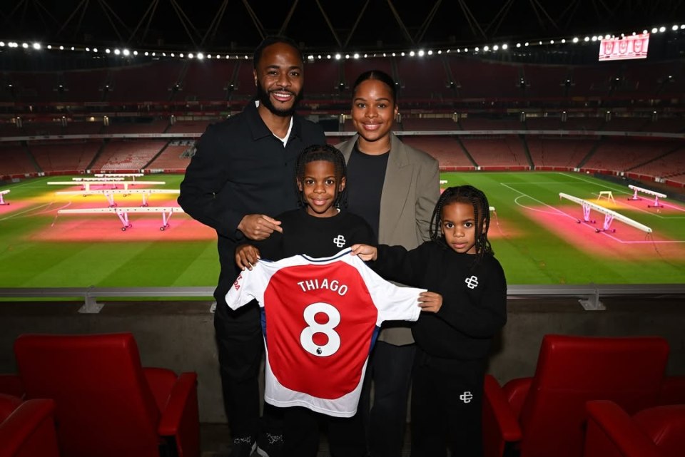 Raheem Sterling's family at an Arsenal stadium, holding his son Thiago's Arsenal jersey.