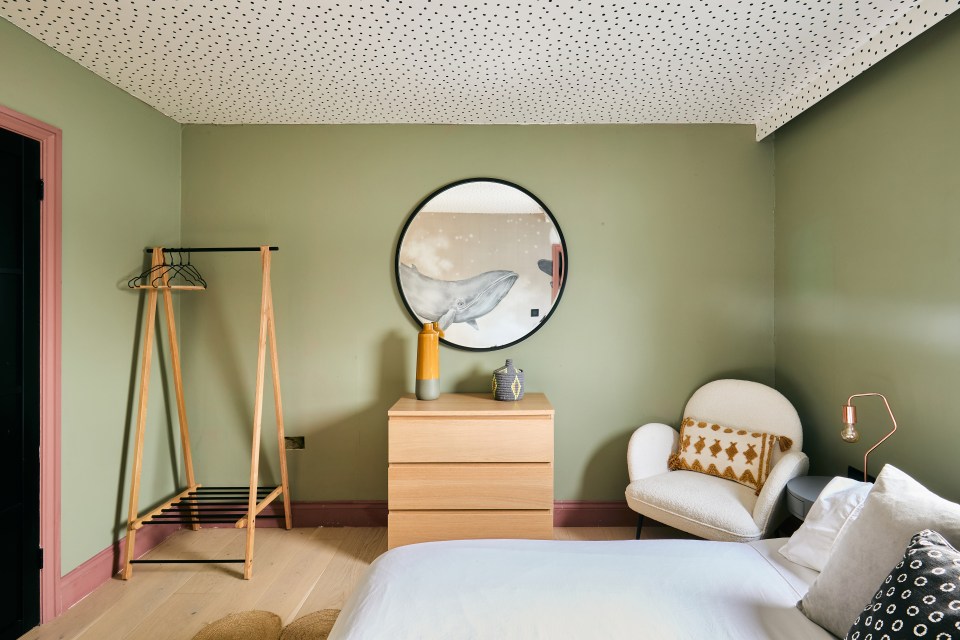 Bedroom with green walls, a whale-themed mirror, and a light wood dresser.