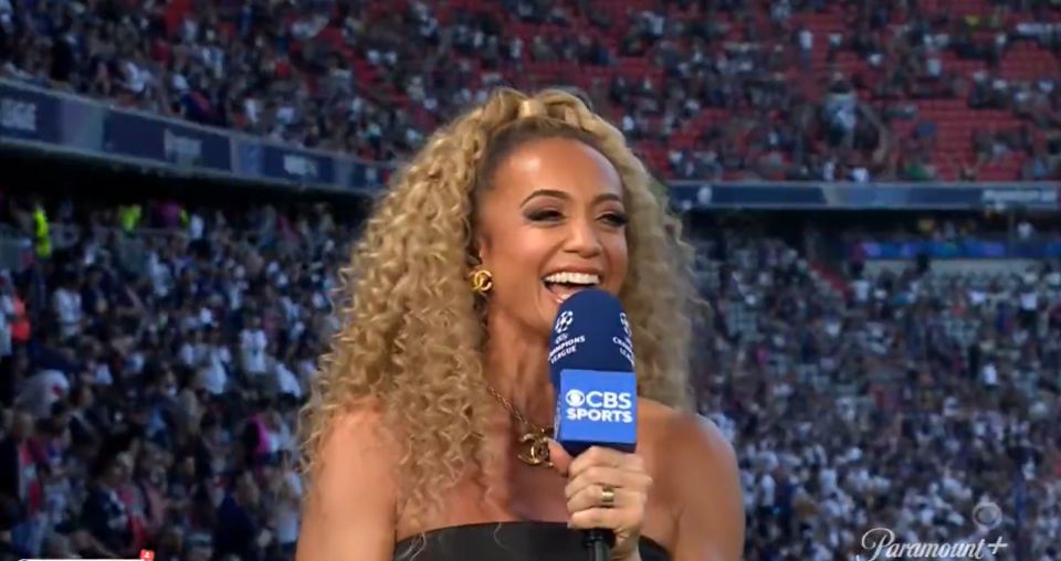Kate Abdo smiling into a CBS Sports microphone at a stadium.