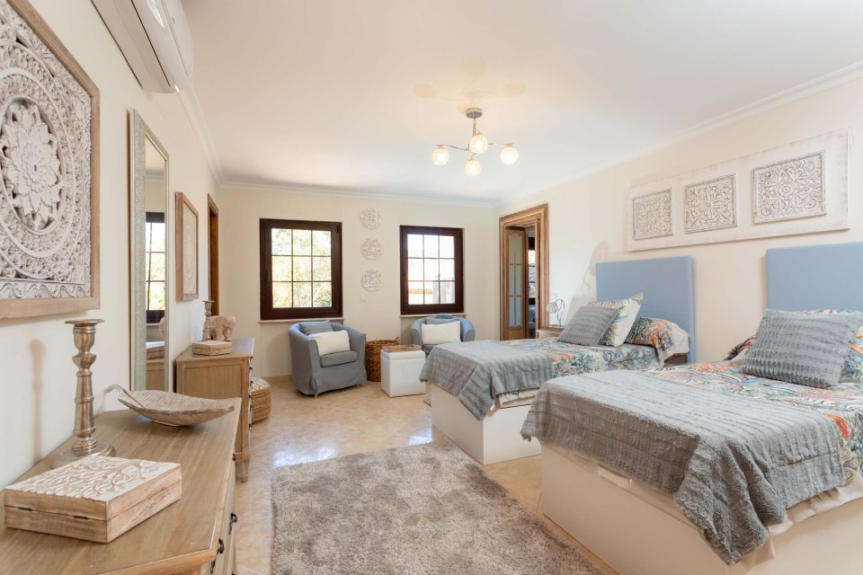Bedroom with twin beds, seating area, and decorative wall art.