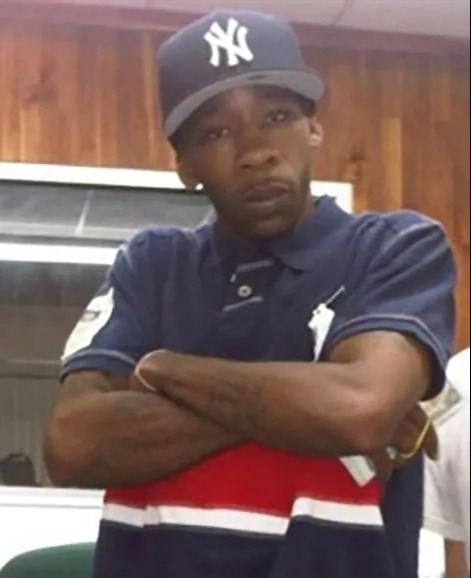 Man wearing a New York Yankees baseball cap and a navy polo shirt with red and white stripes.