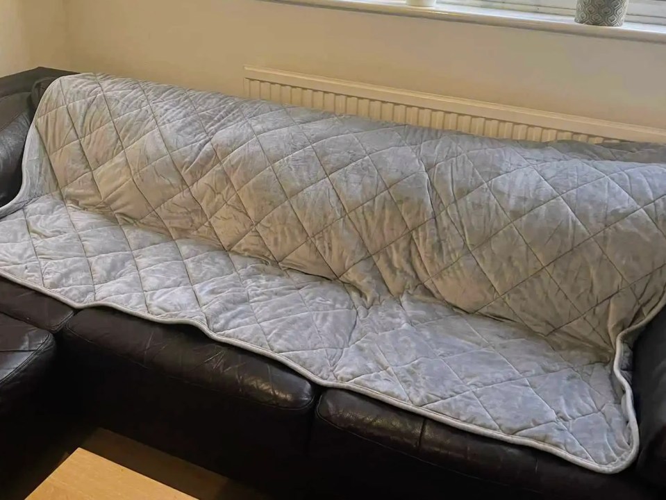 Grey quilted weighted blanket on a couch.