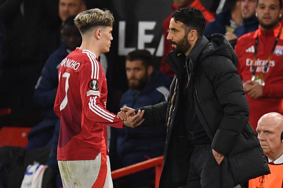 Alejandro Garnacho shaking hands with his coach after being substituted during a soccer match.