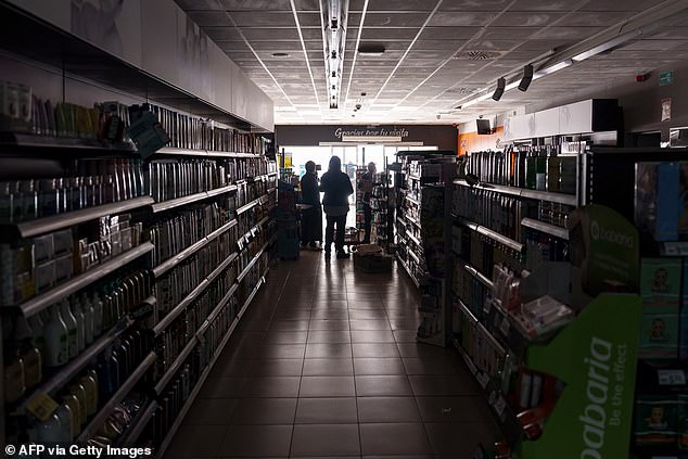 People stand inside a supermarket without lights in Burgos on April 28, 2025, amid the outages