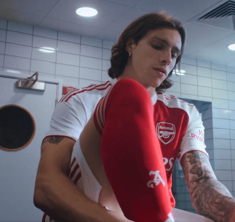 Arsenal soccer player putting on socks.