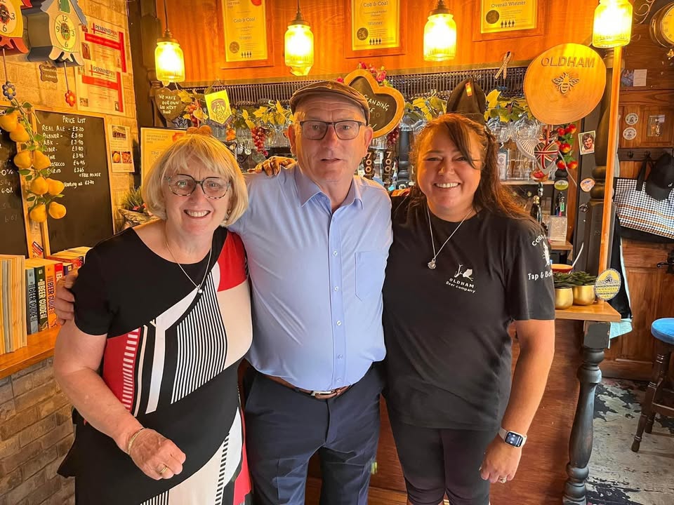 Three people stand in a pub.