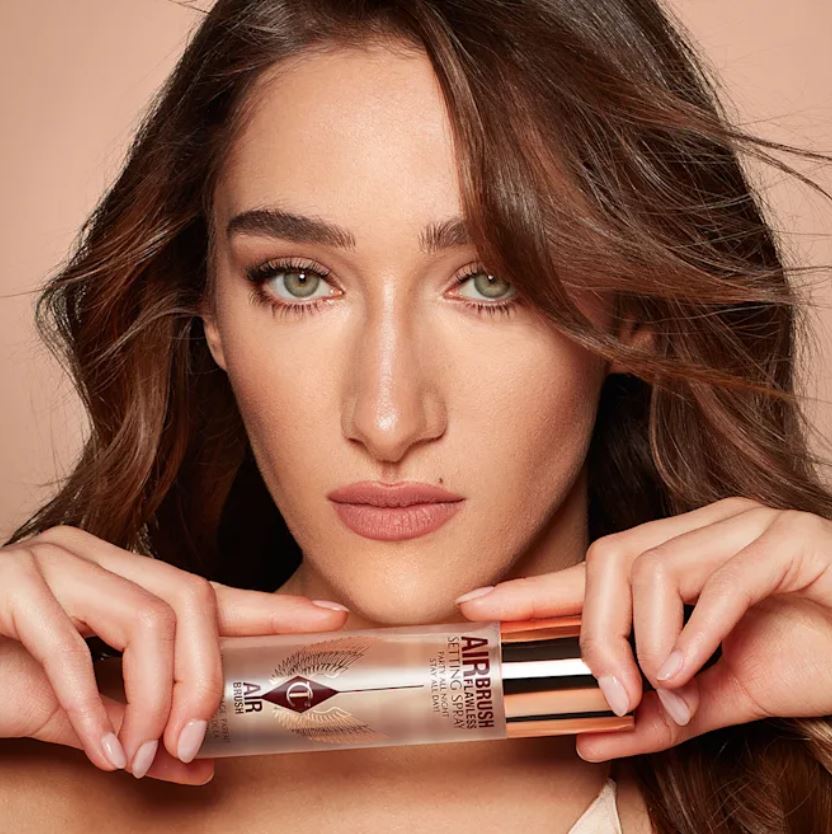 Woman holding a bottle of Airbrush Flawless Setting Spray.