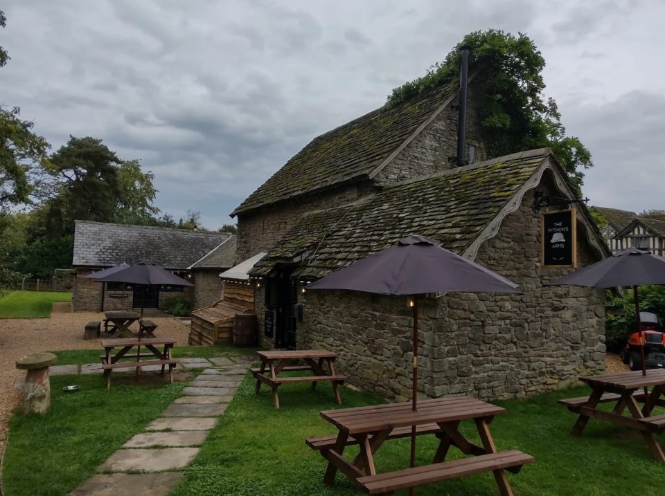 The Python's Arms pub at Penrhos Court with picnic tables and umbrellas.
