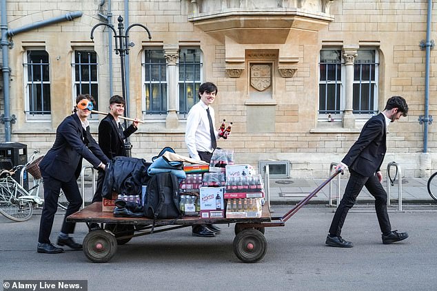 Bleary-eyed Oxford University students were seen making their way home from a May Ball in the early hours of this morning after dancing the night away. One group, which included a man holding a croquet mallet, pushed a wagon carrying crates of beer, a pair of shoes, and various other items down the road