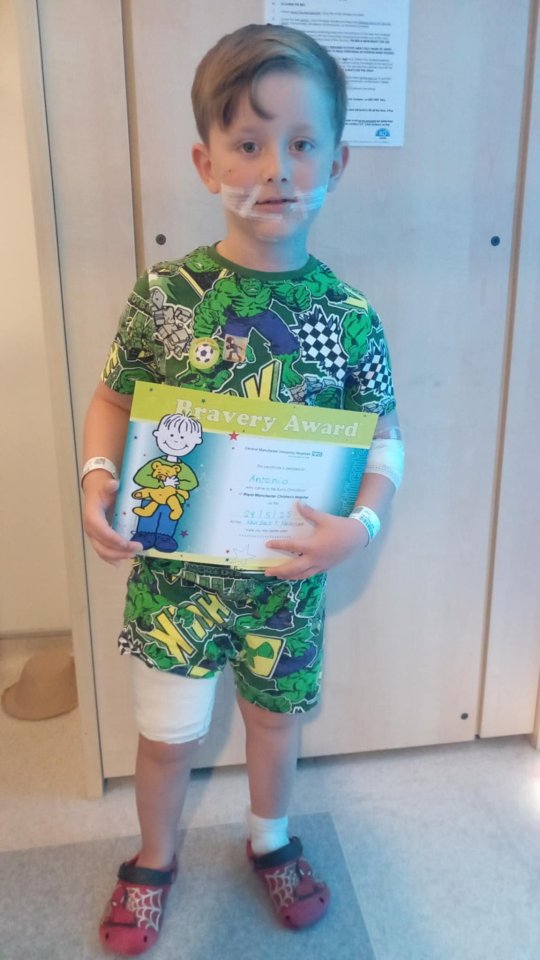 Boy holding bravery award after dog attack.