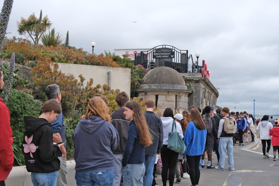 Long queue of people waiting outside Harry Ramsden's fish and chip shop.