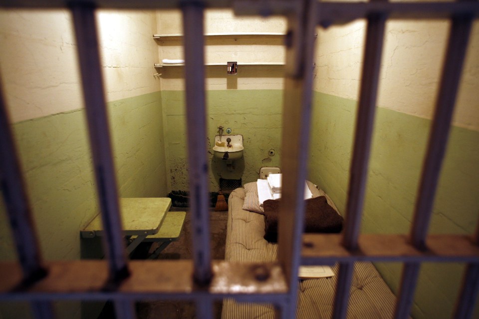 Alcatraz prison cell interior viewed through bars.