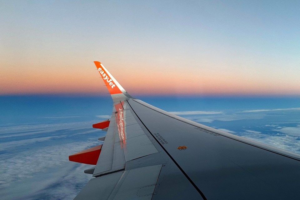 EasyJet wing during sunset viewed from airplane window.