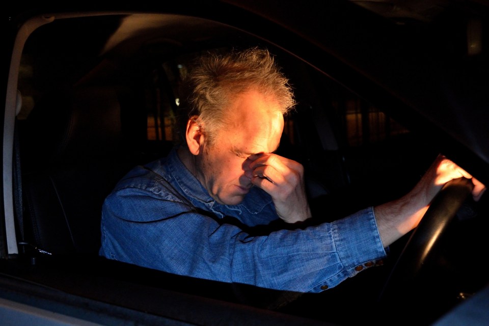 Tired driver rubbing his eyes while driving at night.