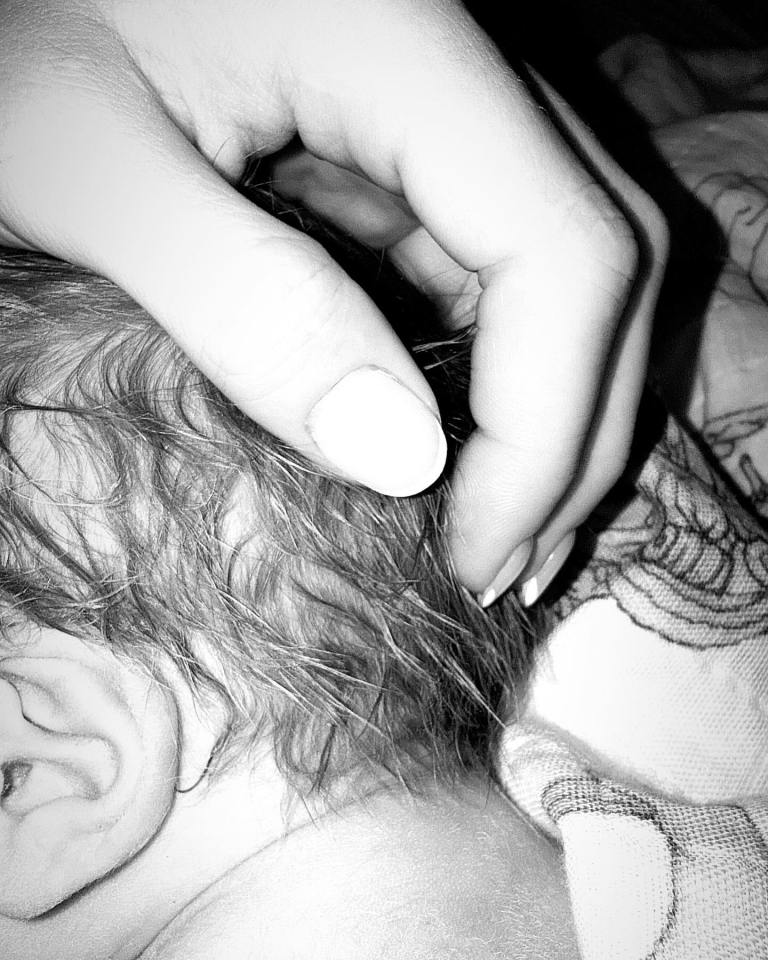 Hand gently touching a baby's head.