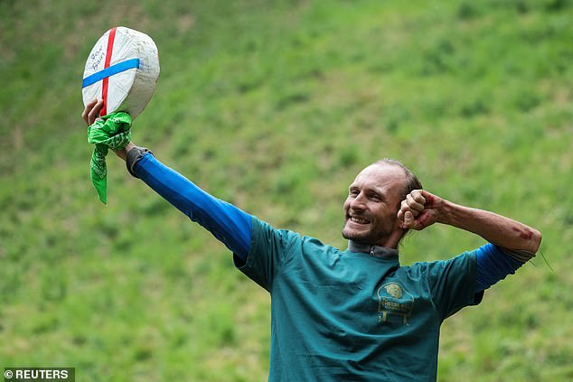 Luke Briggs holds a cheese wheel after winning the second men's race
