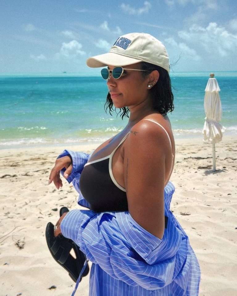 Woman in a swimsuit and hat on a beach.