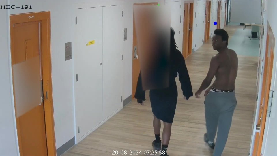 CCTV footage of two people walking down a prison corridor.