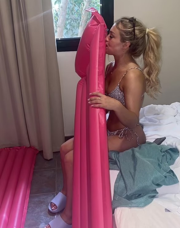 Woman in bikini inflating a pink inflatable raft.