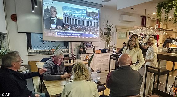 Journalists and residents of Schiavon, northern Italy, hometown of Cardinal Pietro Parolin, gather at the Caffe' Centrale, Wednesday, May 7, 2025, to watch a live TV broadcast from the Vatican, where Cardinal Parolin is presiding over the conclave where the successor of Pope Francis will be elected. (AP Photo/Colleen Barry)