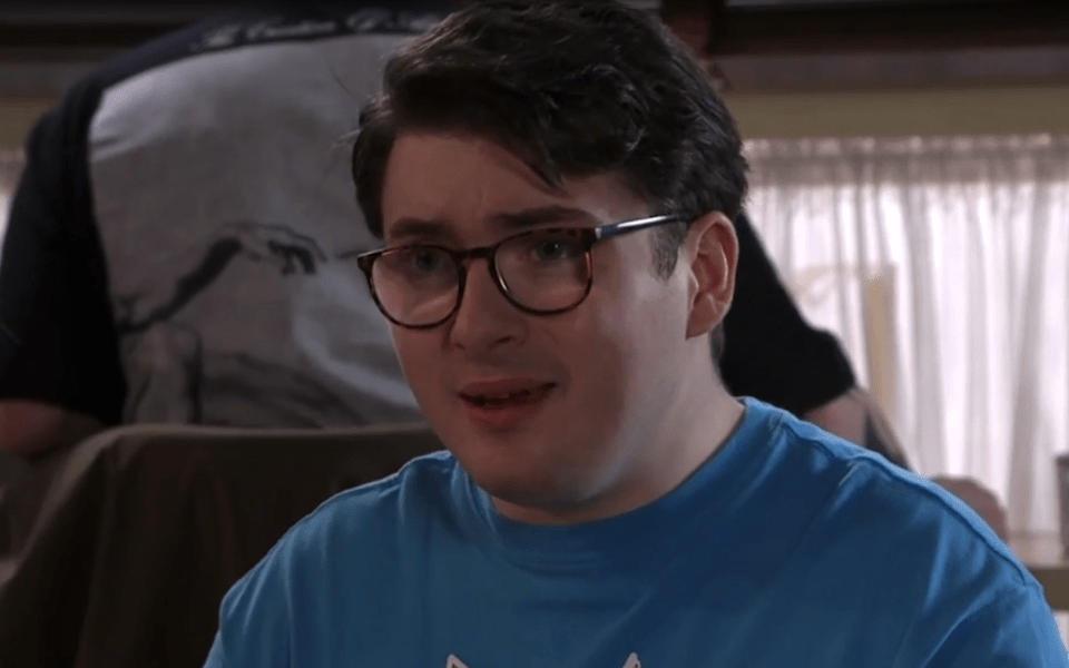 Close-up of a young man wearing glasses and a blue shirt.