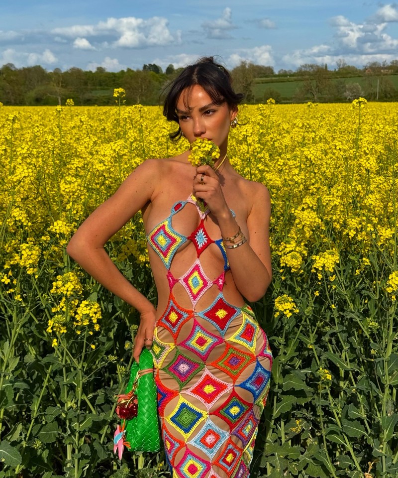 Woman in colorful crochet dress in a field of yellow flowers.