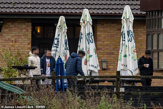 A group of males is seen outside one of the hotels currently housing migrants in November