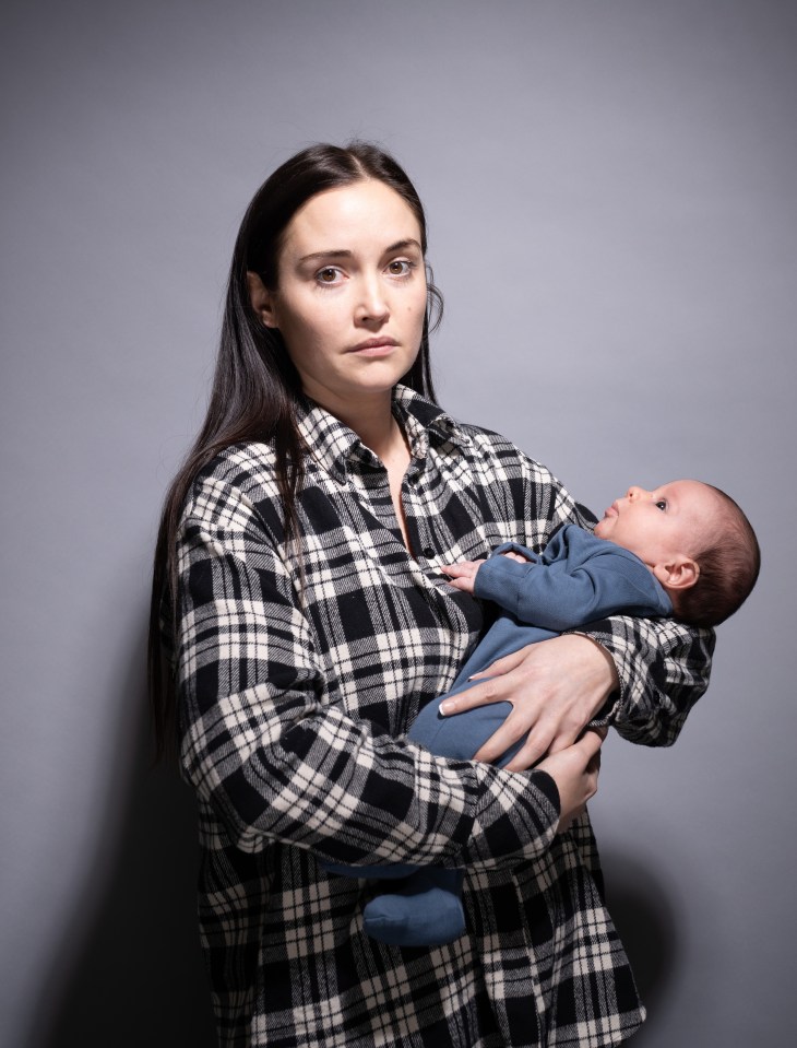 A woman in a plaid shirt holds a baby.