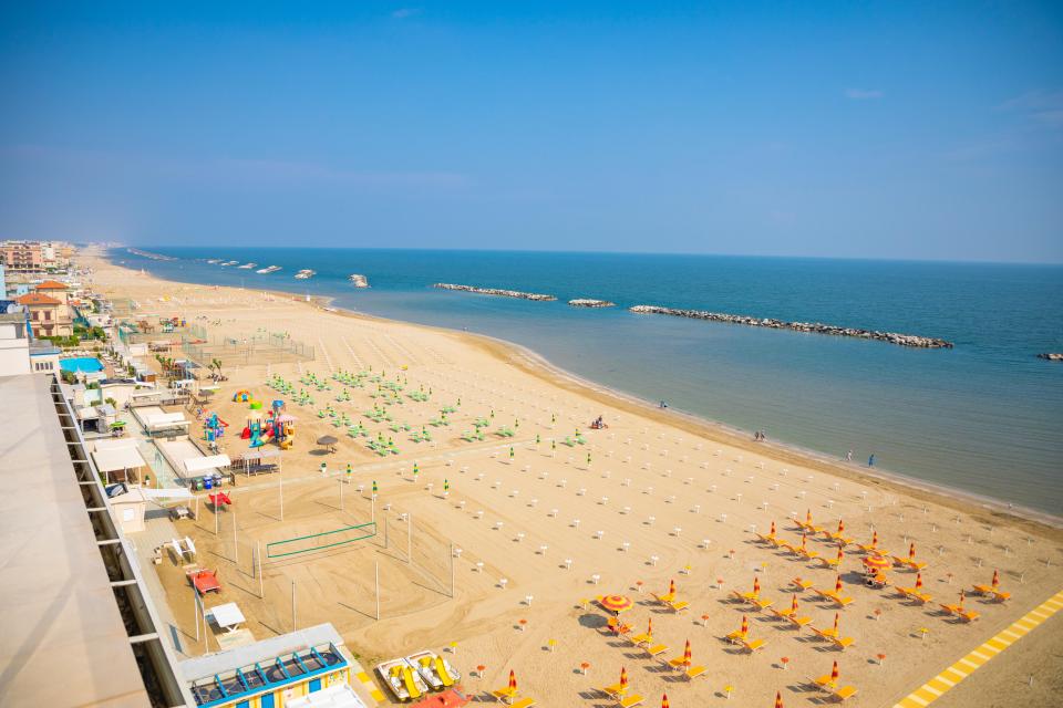Aerial view of Rimini beach with umbrellas and lounge chairs.