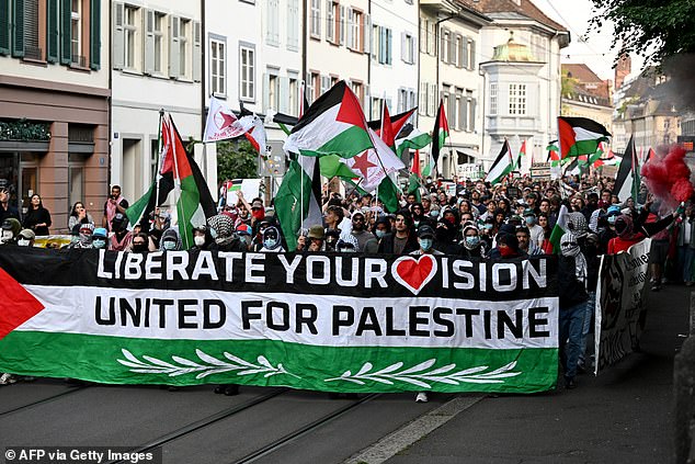 Protestors hold a banner and Palestinian flags during a demonstration against Israel's participation prior to the Eurovision final