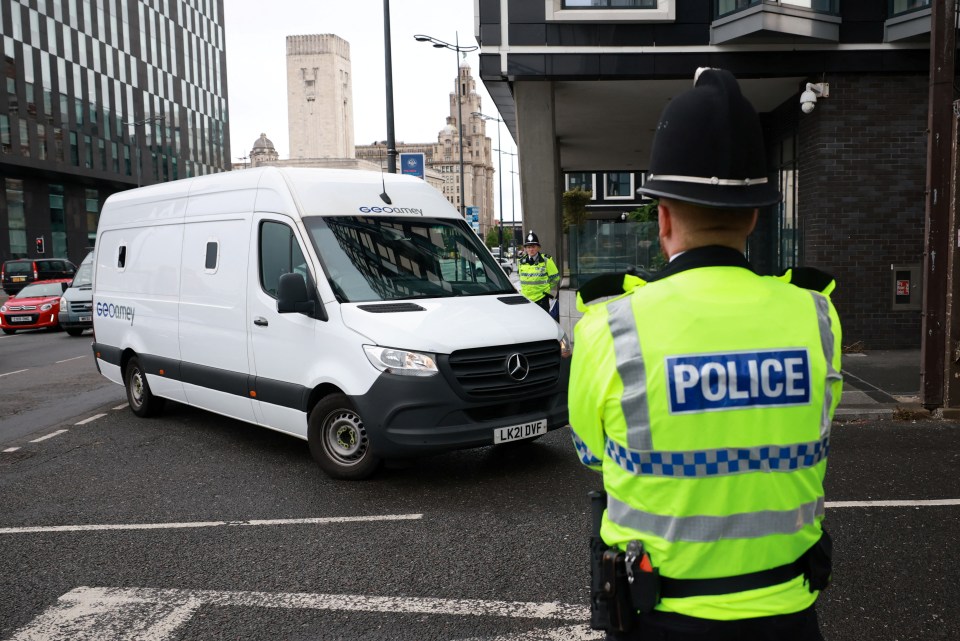 Police officer guarding a prison van.