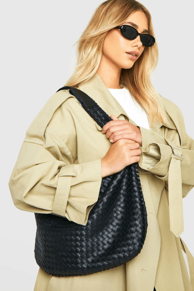 Woman holding a black woven handbag.