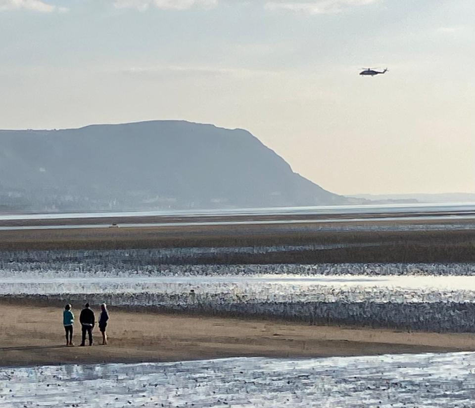 Coastguard helicopter searching a beach.
