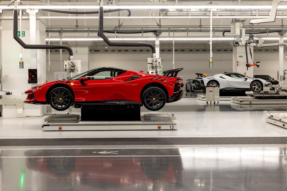 Red and silver sports cars on automated assembly line.
