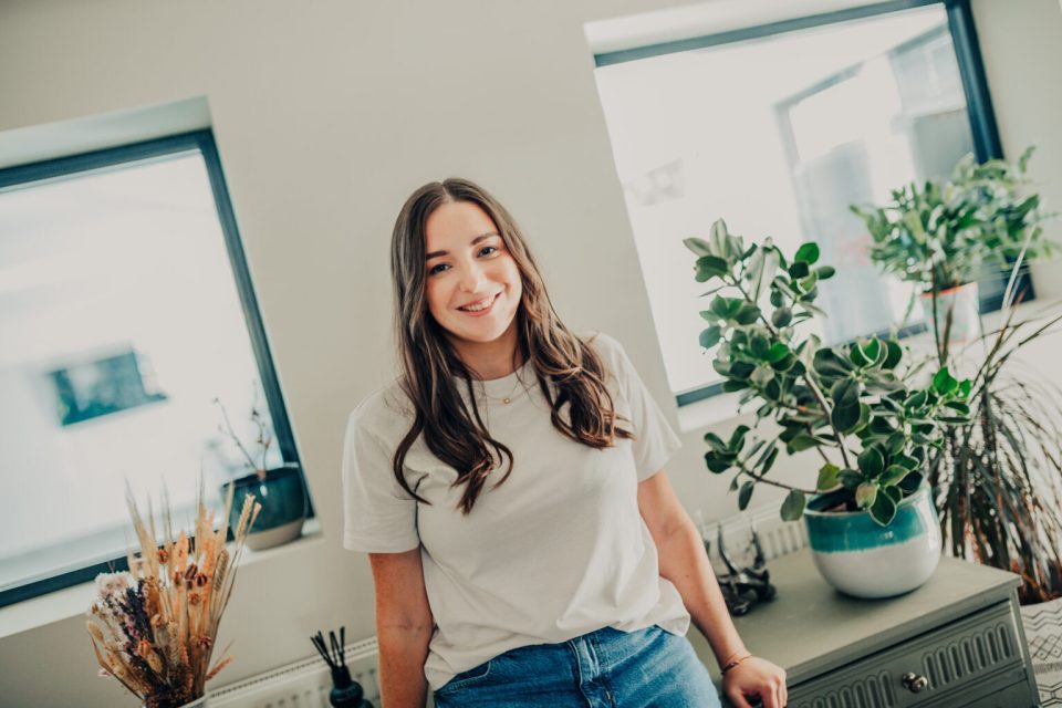 Woman smiling in a white t-shirt and jeans.