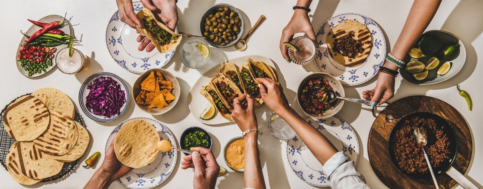 Overhead view of friends enjoying a Mexican taco dinner.