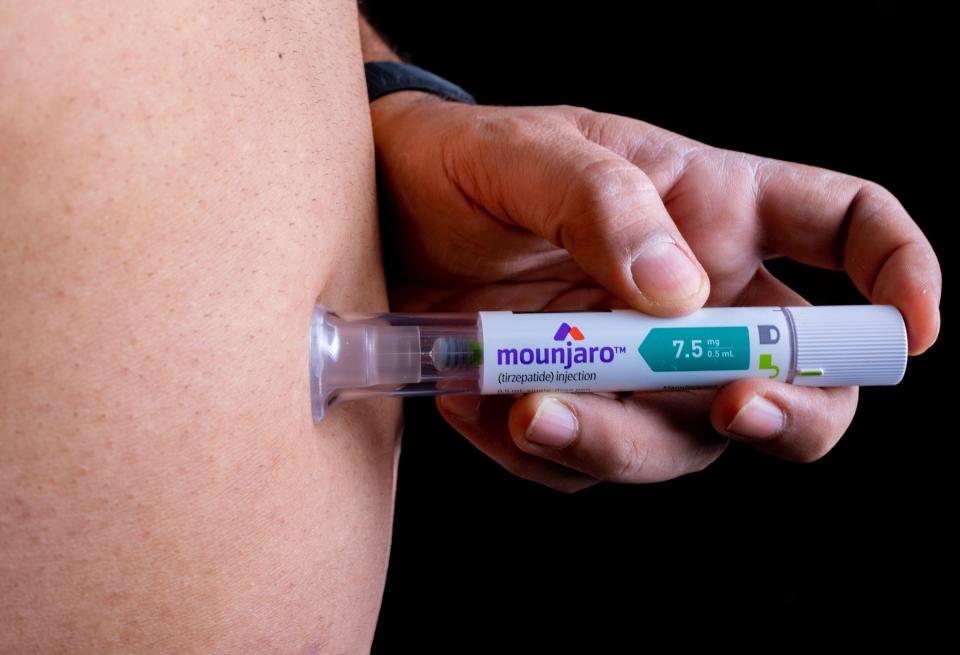 Person injecting Mounjaro pen.