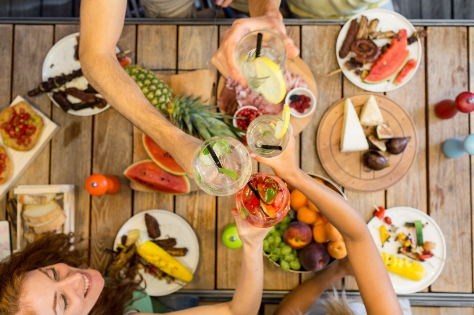 Friends toasting with cocktails at an outdoor dinner party.