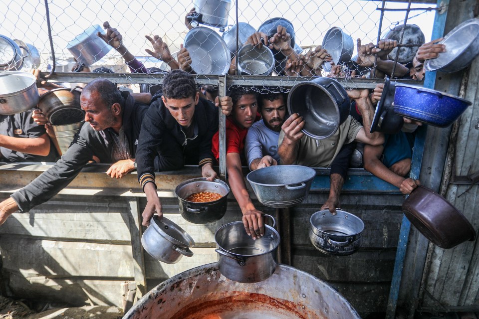 Displaced Palestinians, including women and children, receive food aid.