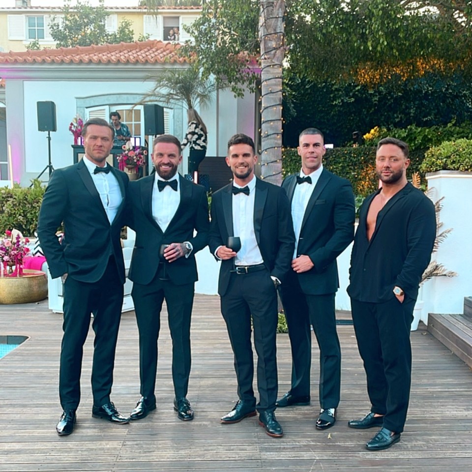 Five men in black tuxedos at an outdoor event.