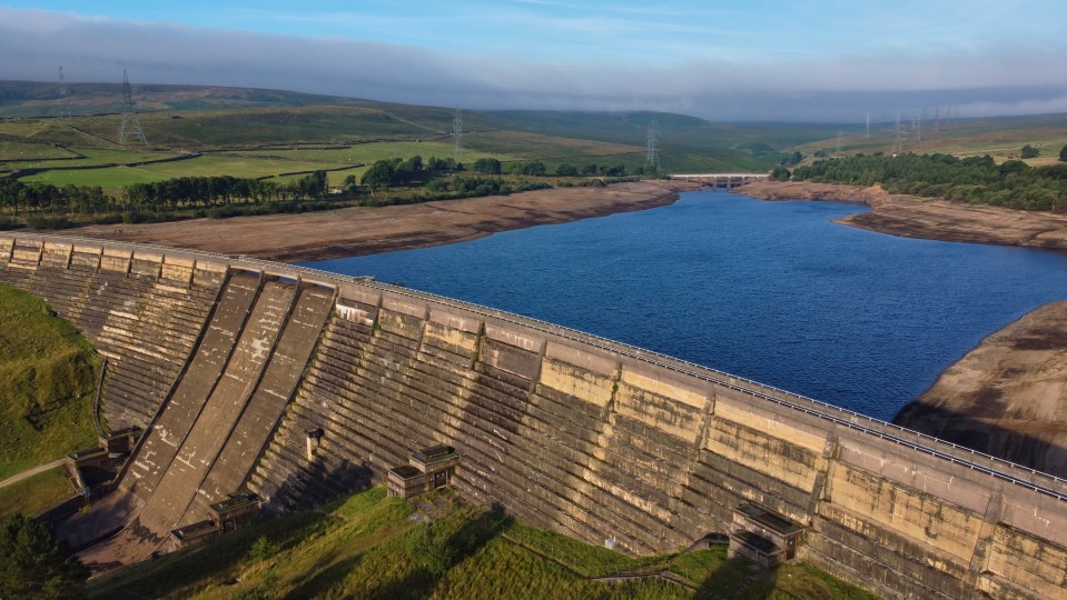 Aerial view of a dam and reservoir with low water levels.