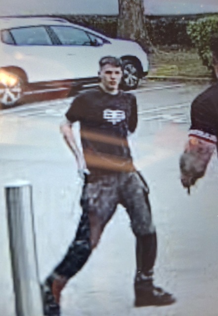 Security camera image of a man in a dark shirt and camouflage pants.