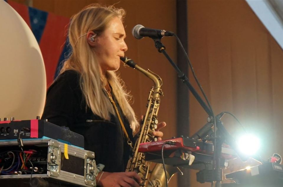 Woman playing saxophone and keyboard at Glastonbury Festival.