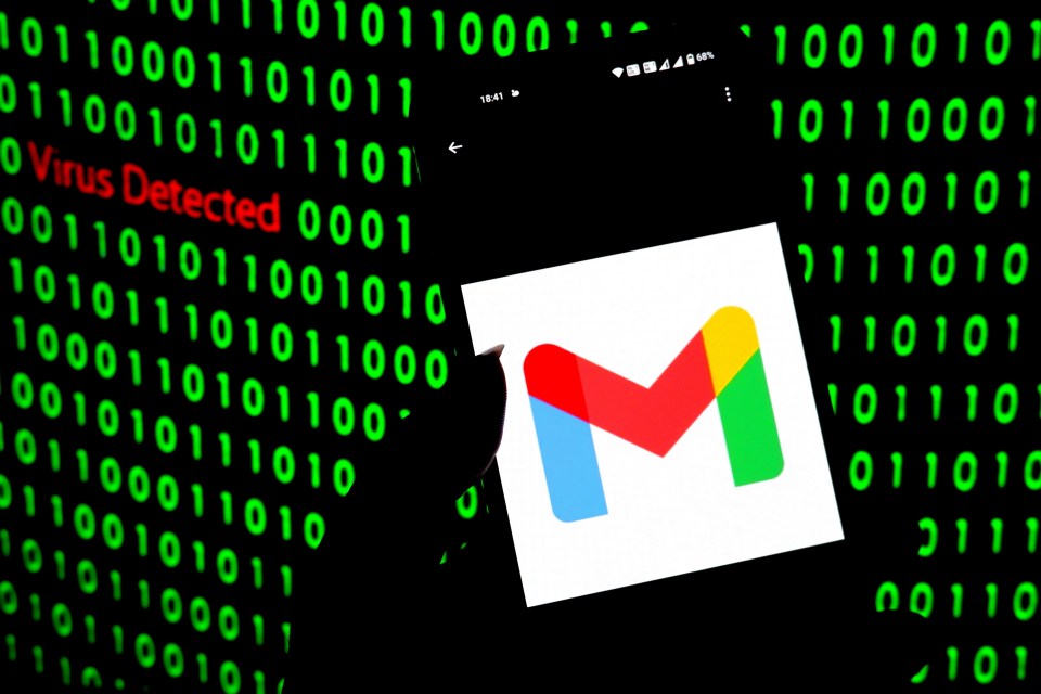 Photo illustration of a Gmail logo on a smartphone screen with a "Virus Detected" message and binary code in the background.
