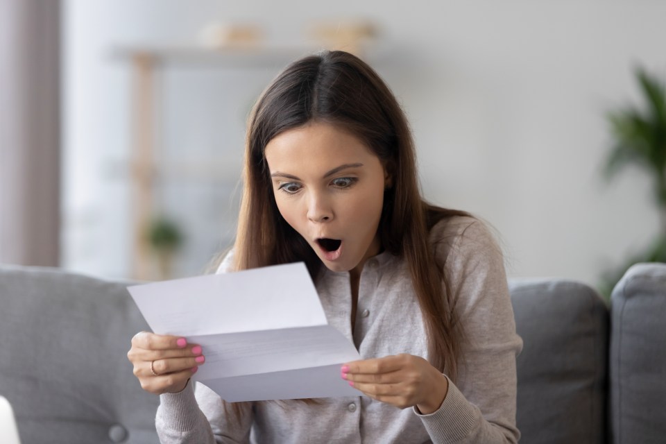 A surprised young woman reads a letter.