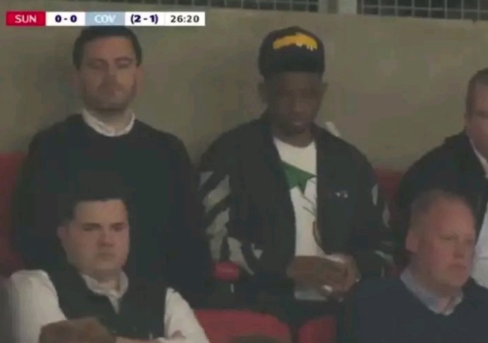 Screenshot of people sitting in stadium seats.